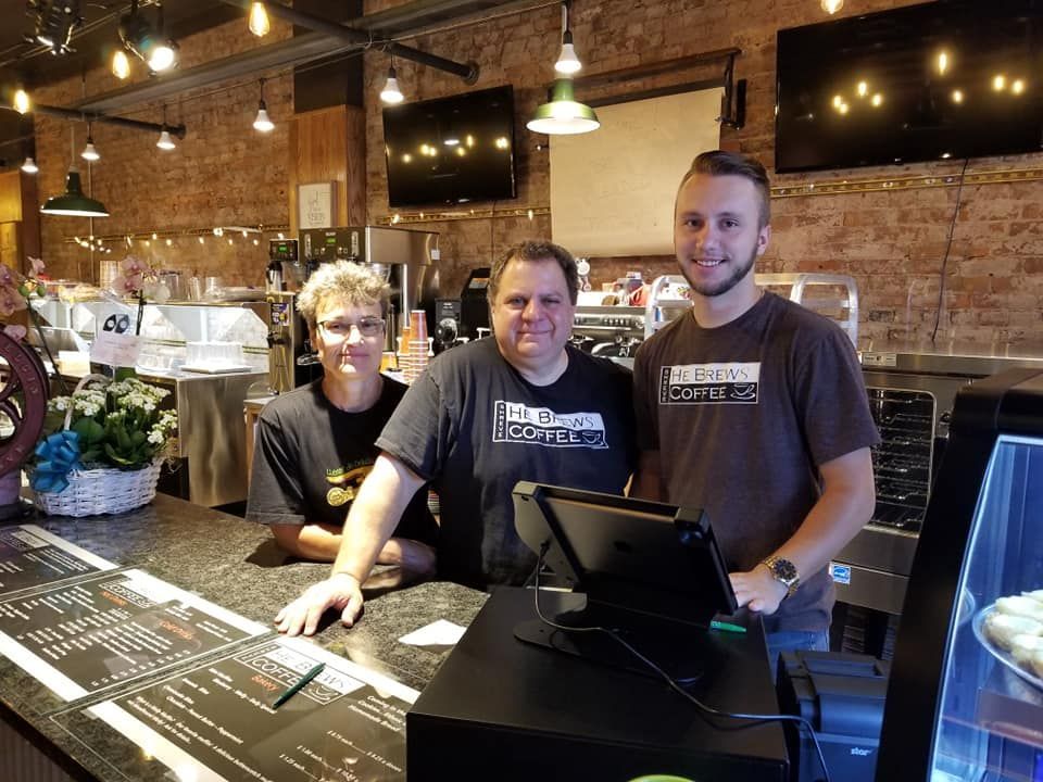 Three people are standing in front of a counter in a restaurant.