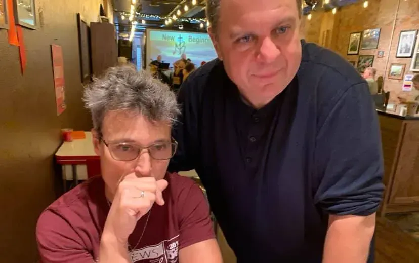 Two men are standing next to each other in a restaurant.