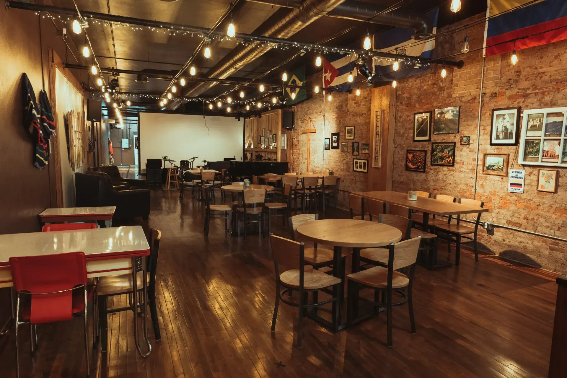 A restaurant with tables and chairs and a large screen on the wall.