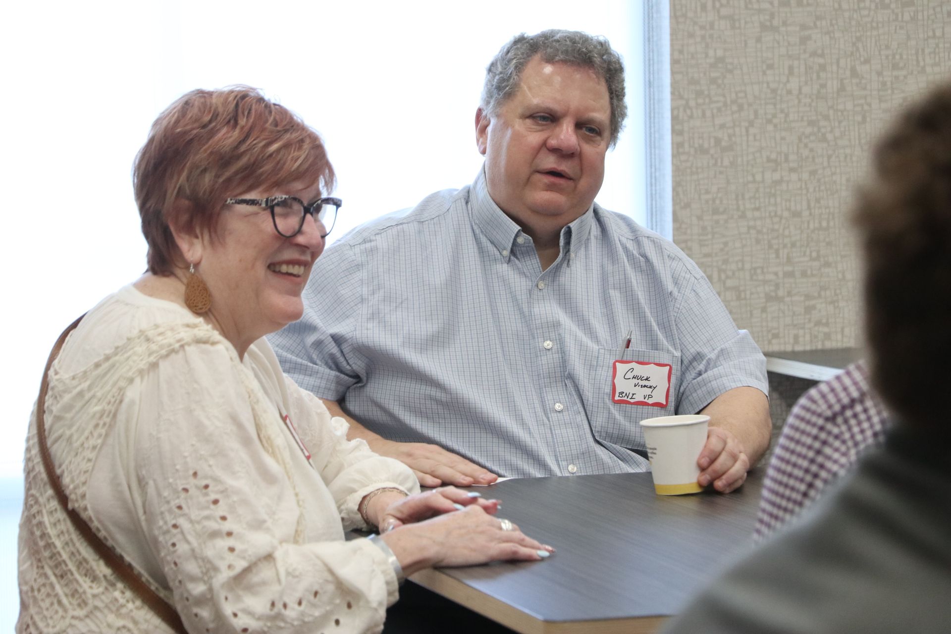 A man and a woman are sitting at a table talking to each other.