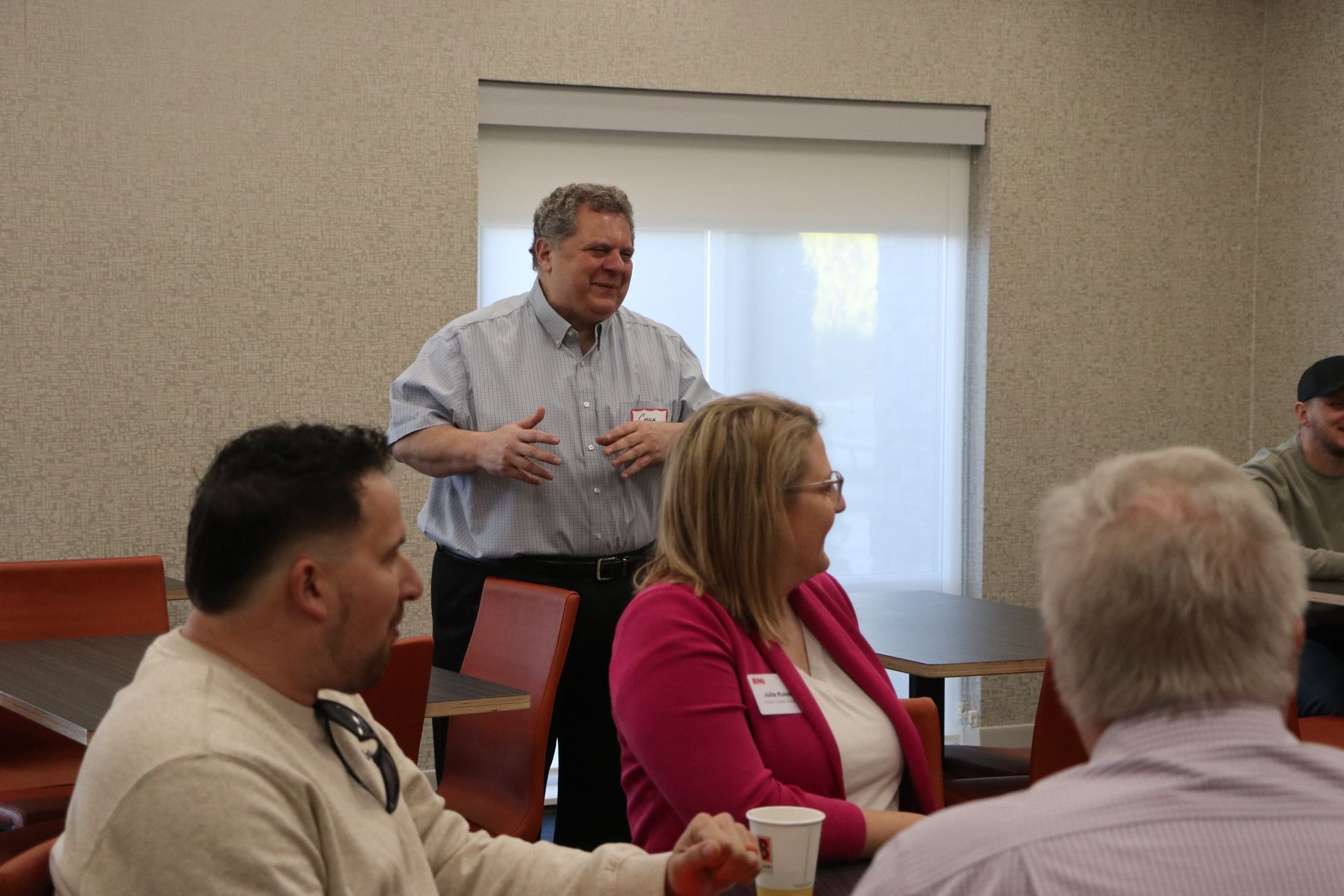 A man is standing in front of a group of people sitting at tables.