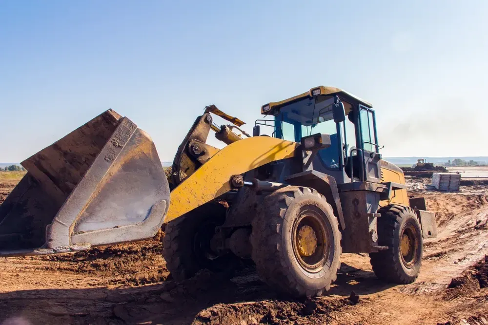 Yellow front-end loader on a construction site with the bucket raised, on a sunny day. — Shantui QLD in Warwick, QLD