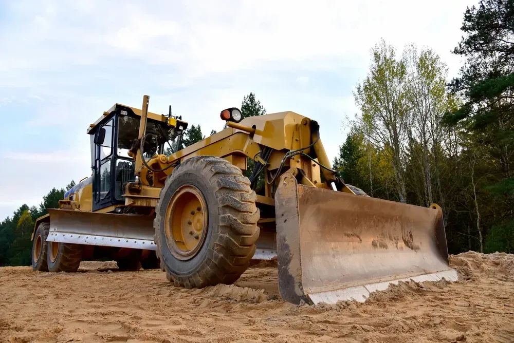 Yellow motor grader on gravel, blade lowered, under a blue sky. — Shantui QLD in Roma, QLD