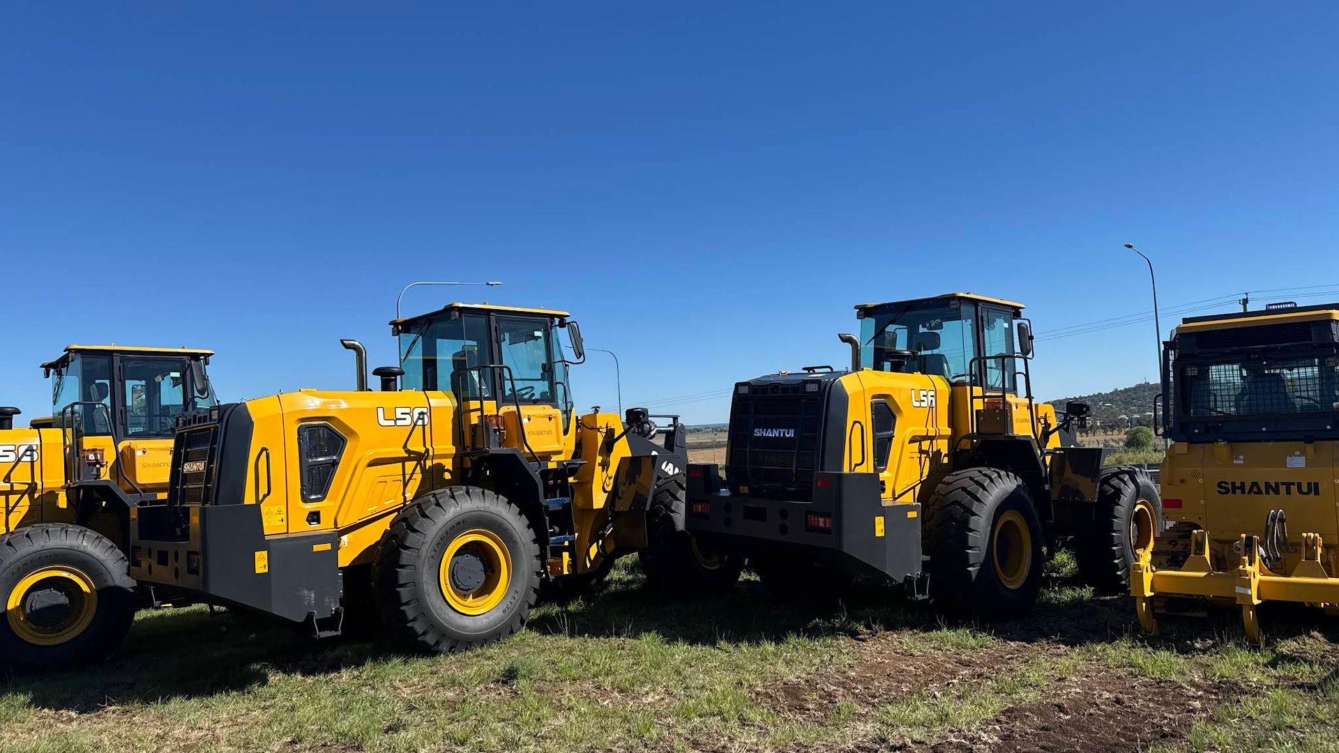 Four Yellow Construction Vehicles Parked Outdoors Under a Blue Sky — Shantui QLD in Kingsthorpe, QLD