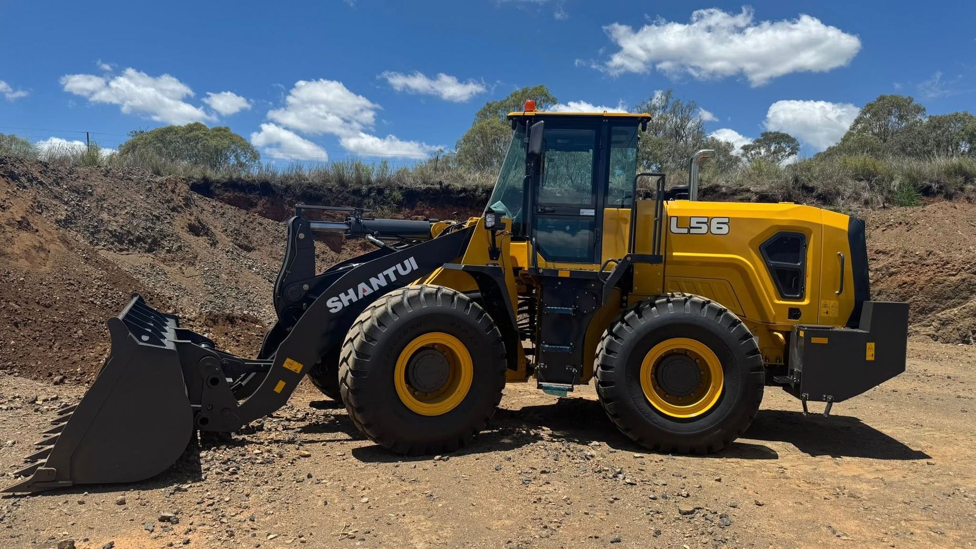 Yellow Shantui wheel loader on a dirt road, with a raised bucket — Shantui QLD in Kingsthorpe, QLD