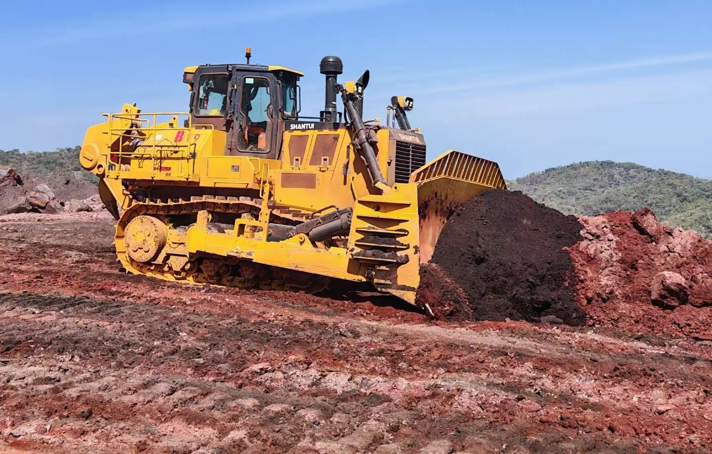 Yellow Bulldozer Pushing a Pile of Dirt and Rocks Under a Blue Sky — Shantui QLD in Dalby, QLD