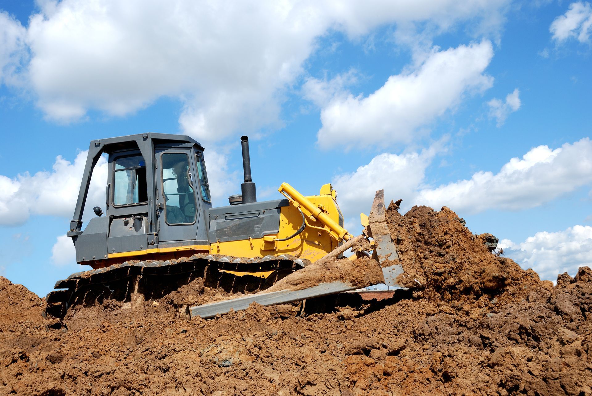 Yellow bulldozer pushing a pile of dirt and rocks on a sunny day — Shantui QLD in Kingsthorpe, QLD