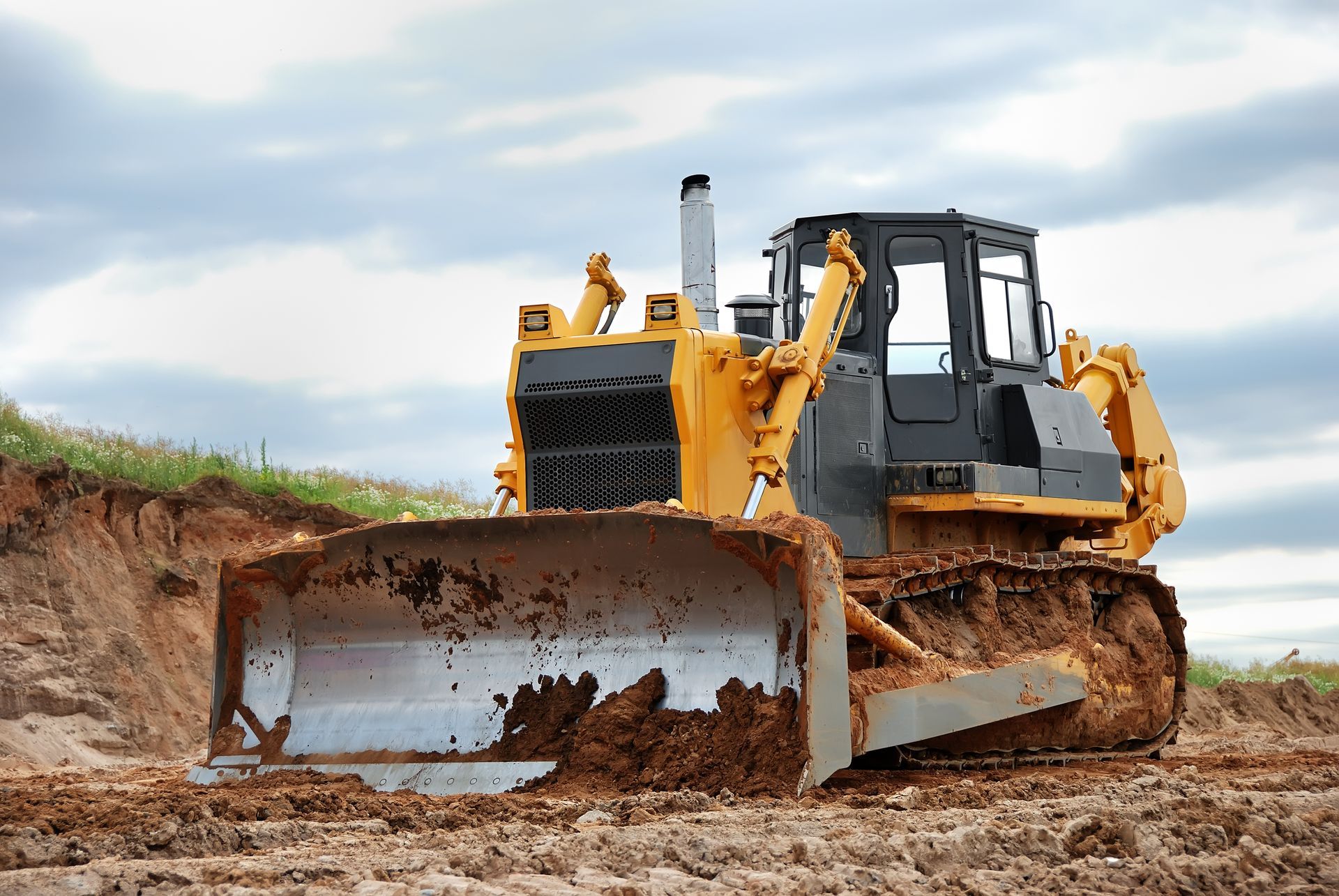 A bulldozer, yellow, grading soil on a construction site