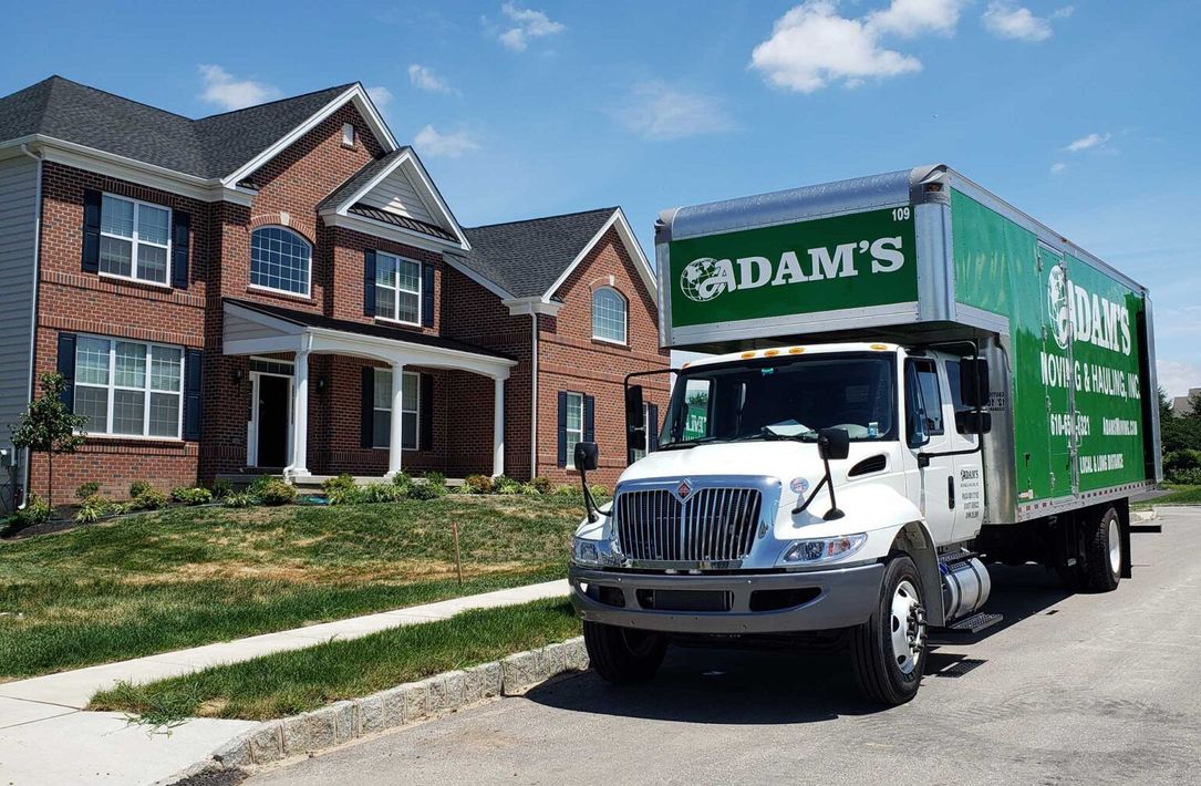 A moving truck is parked in front of a brick house.