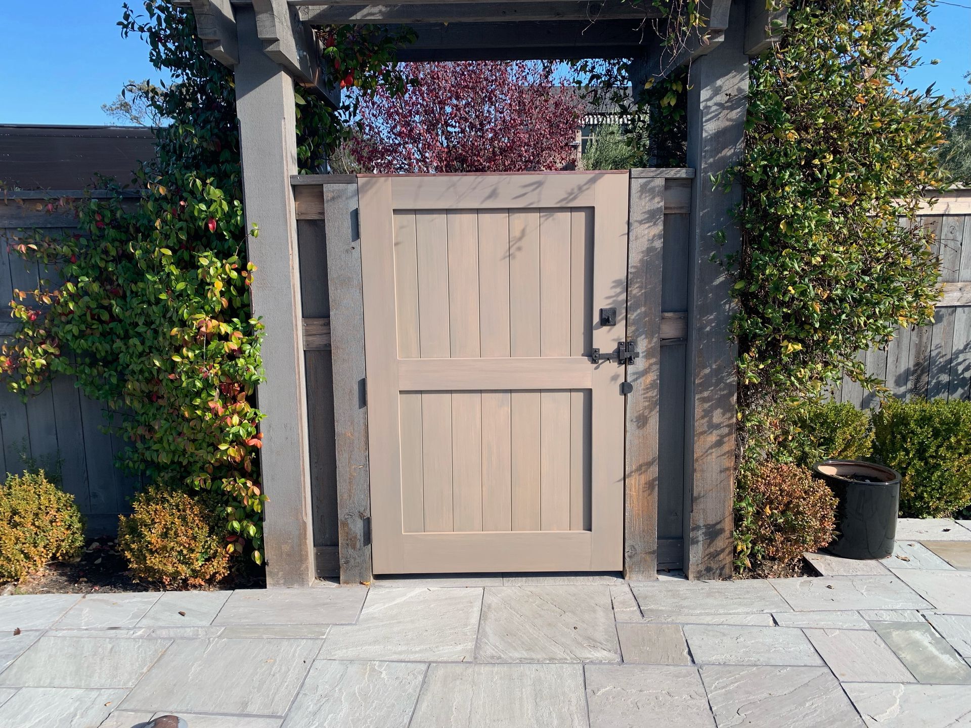 A wooden gate with a pergola behind it