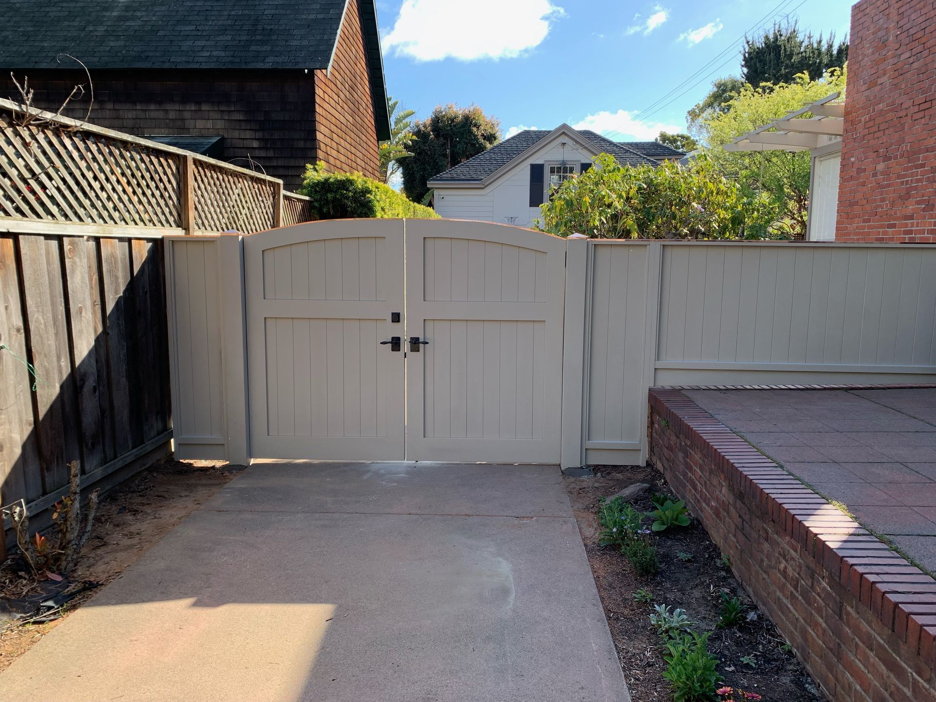 A white wooden gate is open to a driveway