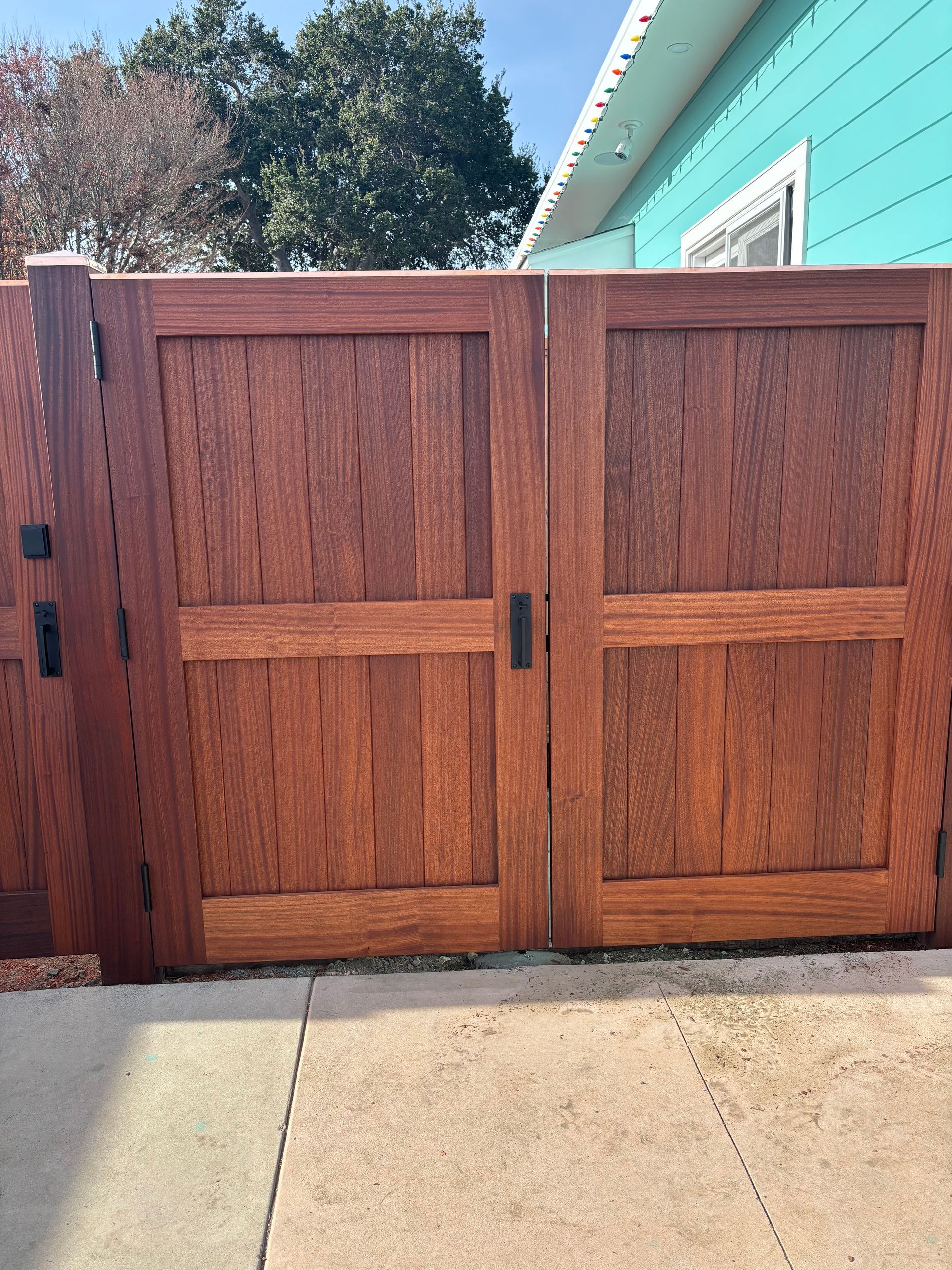 A wooden gate is sitting on the sidewalk in front of a blue house.