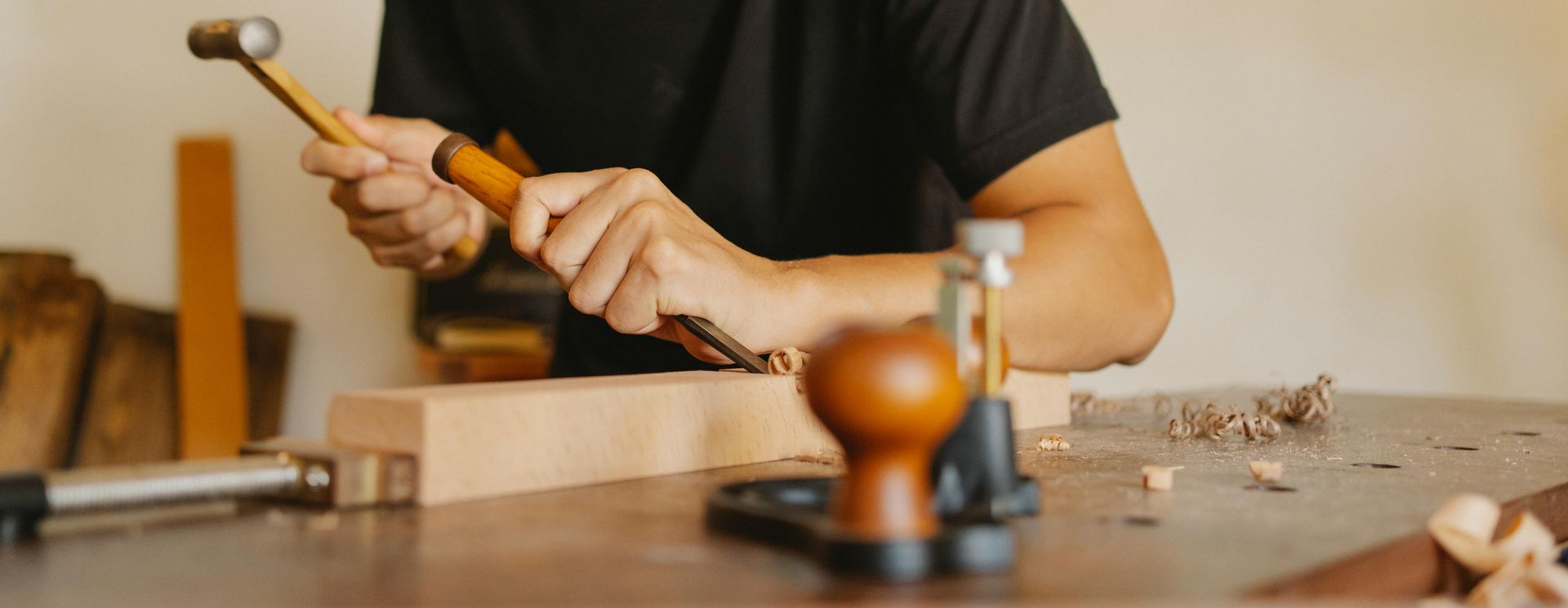 A man is hammering a nail into a piece of wood.