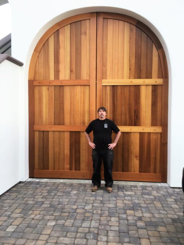A man is standing in front of a large wooden door.