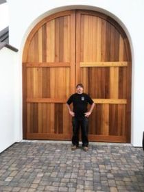 A man is standing in front of a large wooden door.