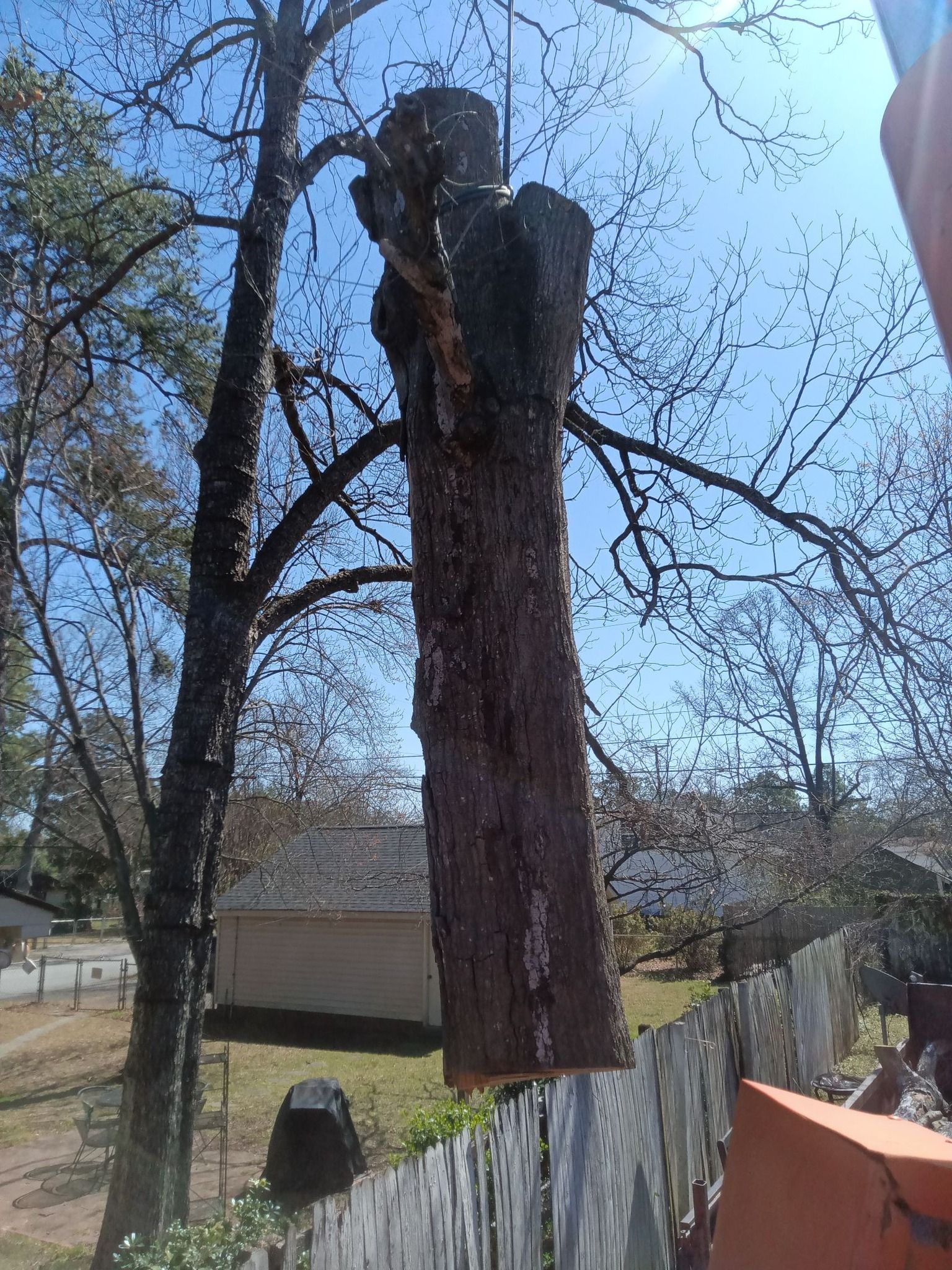 A large tree stump is hanging from a crane.