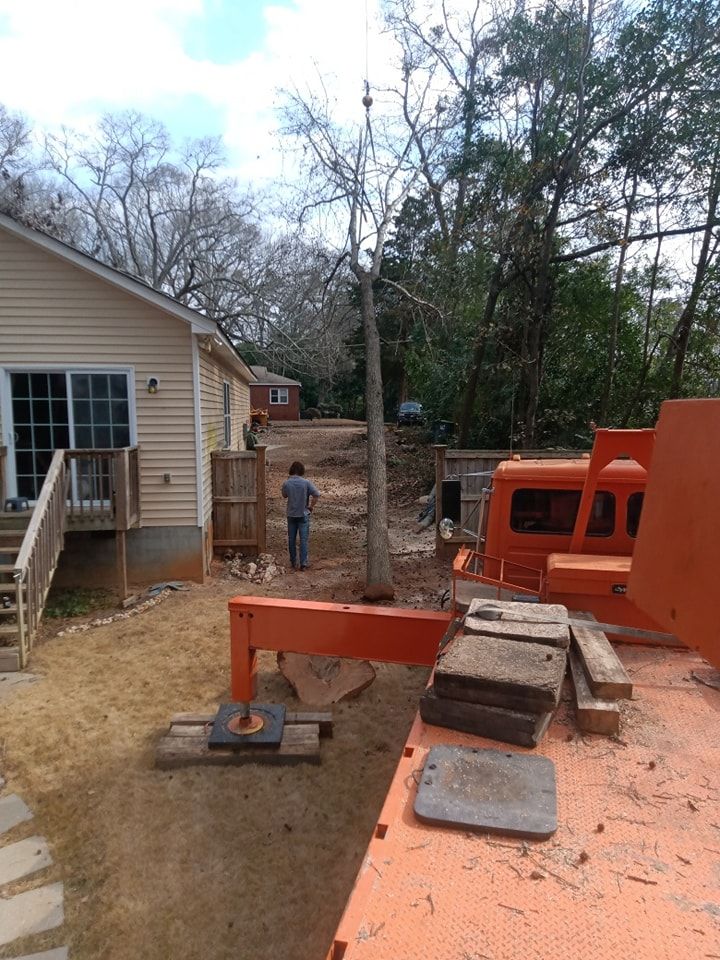 A man is standing in front of a house next to a large orange truck.
