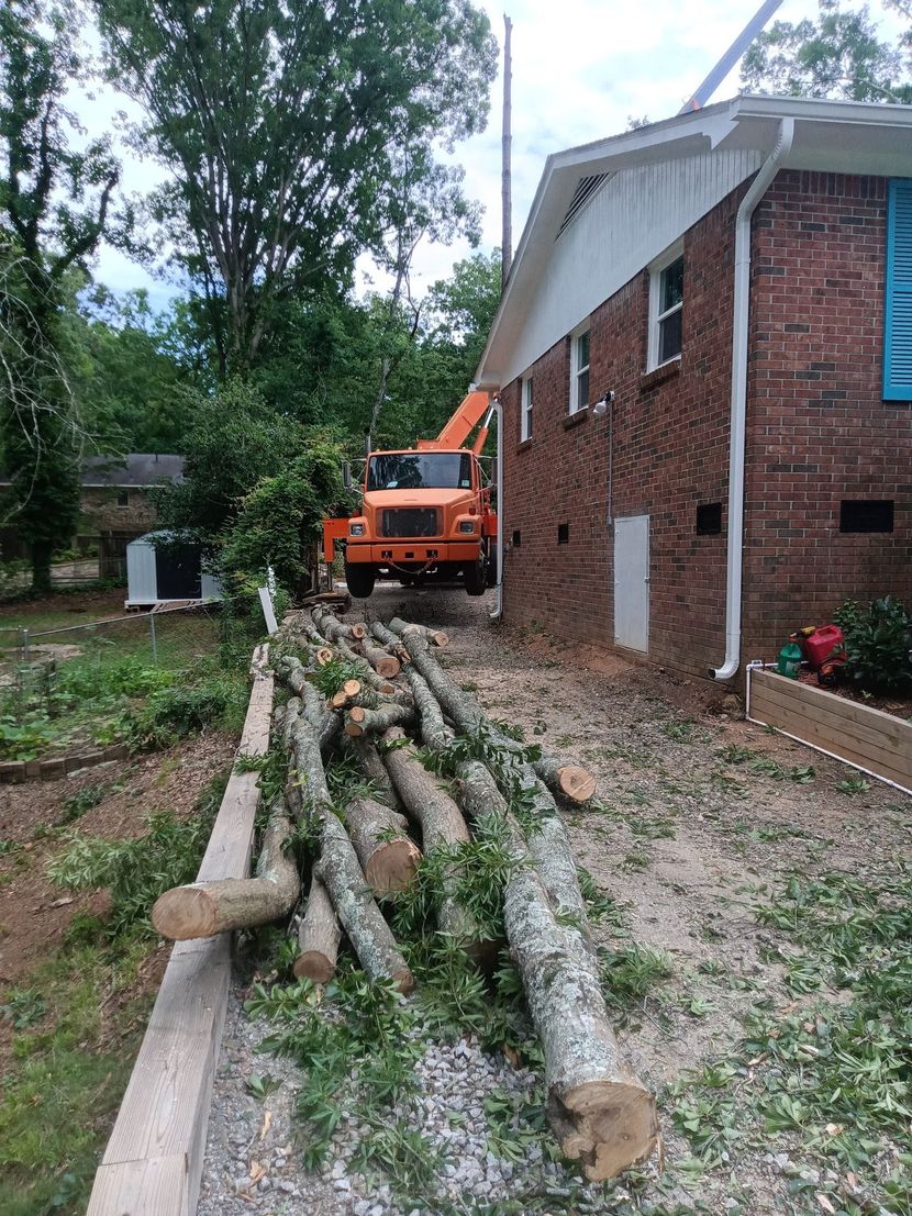 A pile of logs is sitting in front of a brick house.