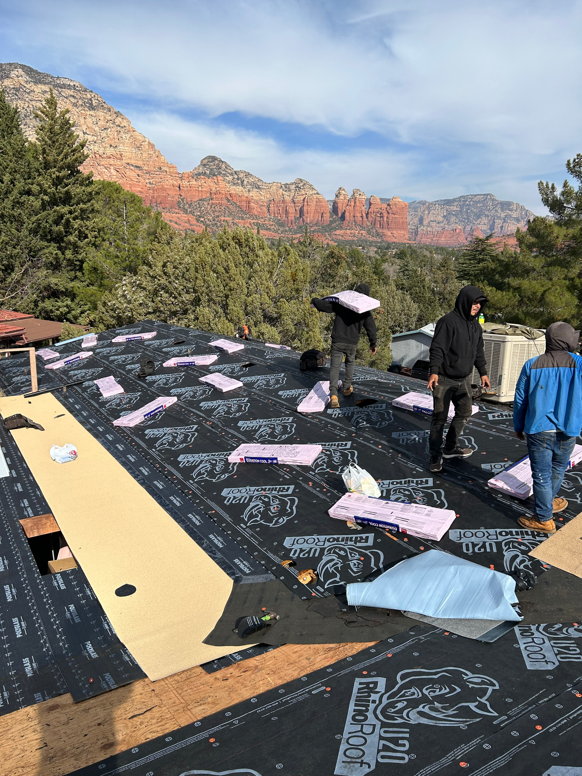 A group of people are working on a roof with mountains in the background