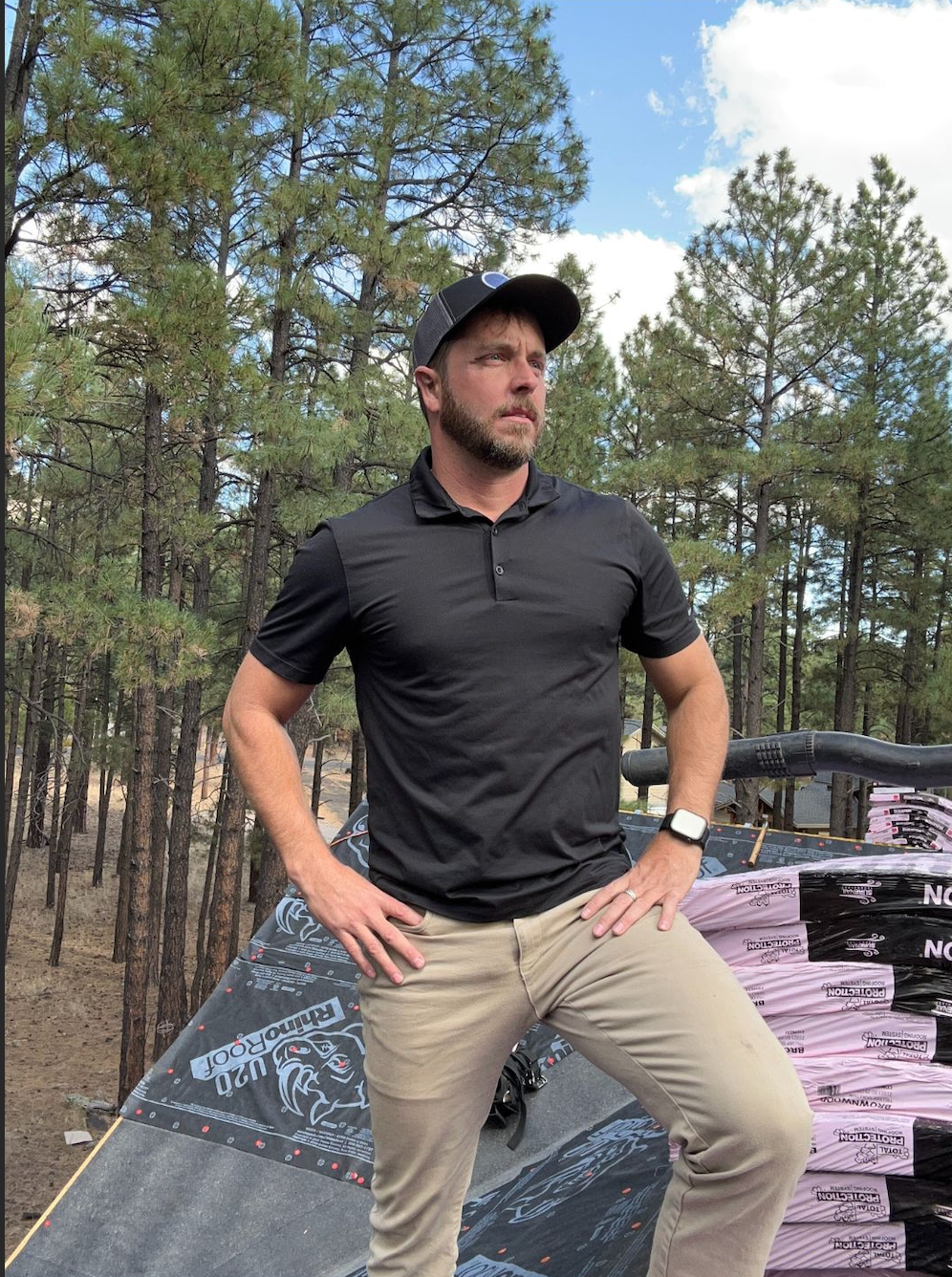 A man is standing on a roof with his hands on his hips.