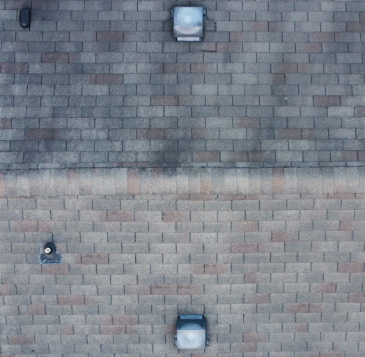 Overhead view of a gray and brown shingled roof with three rectangular vents and one cylindrical pipe.