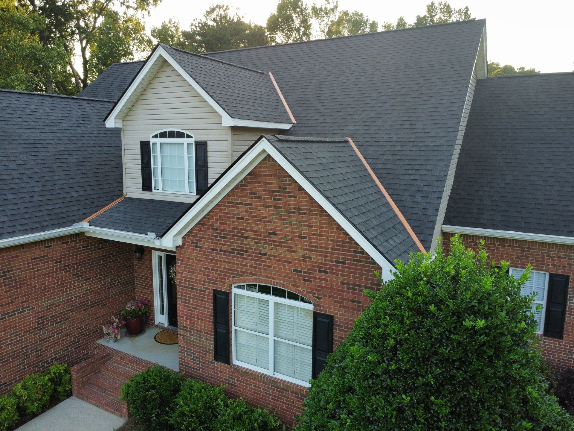 An aerial view of a brick house with a black roof.