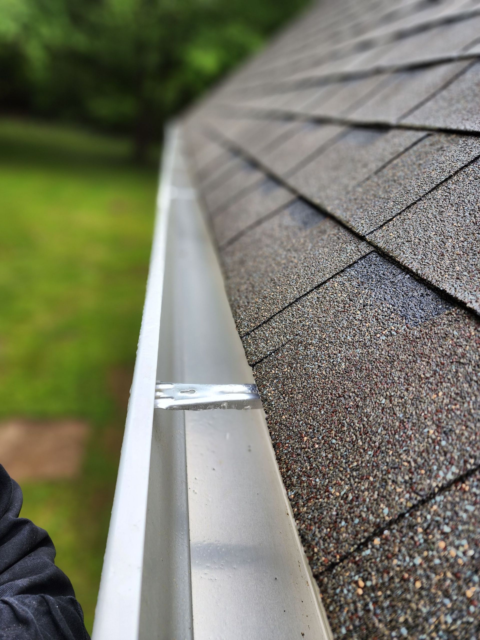 A person is standing next to a gutter on a roof.