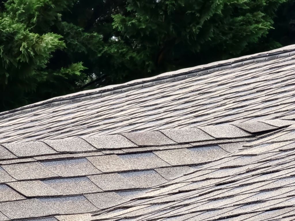 A close up of a roof with a hole in it and trees in the background.