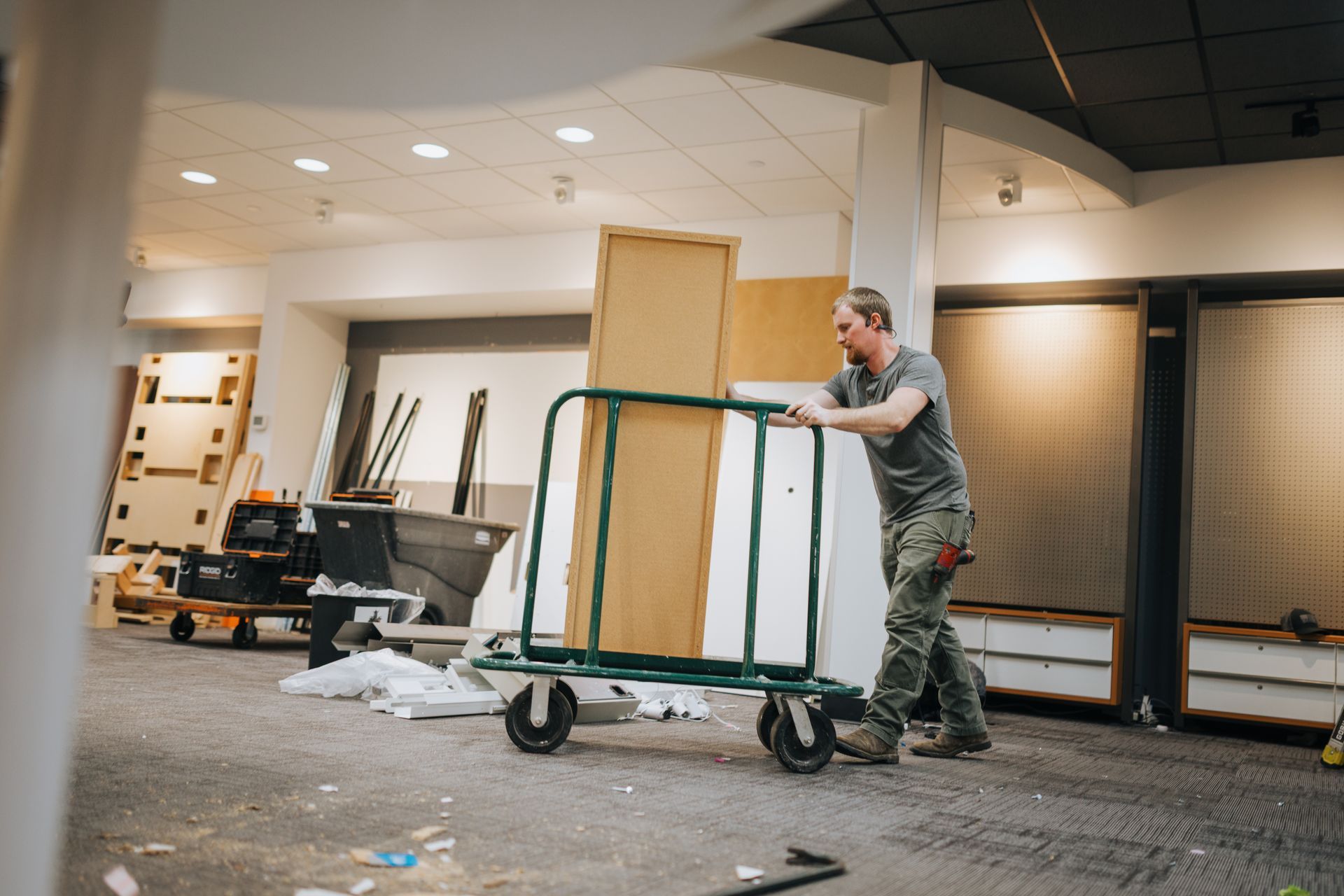 A man is pushing a cart with a door on it in a room.