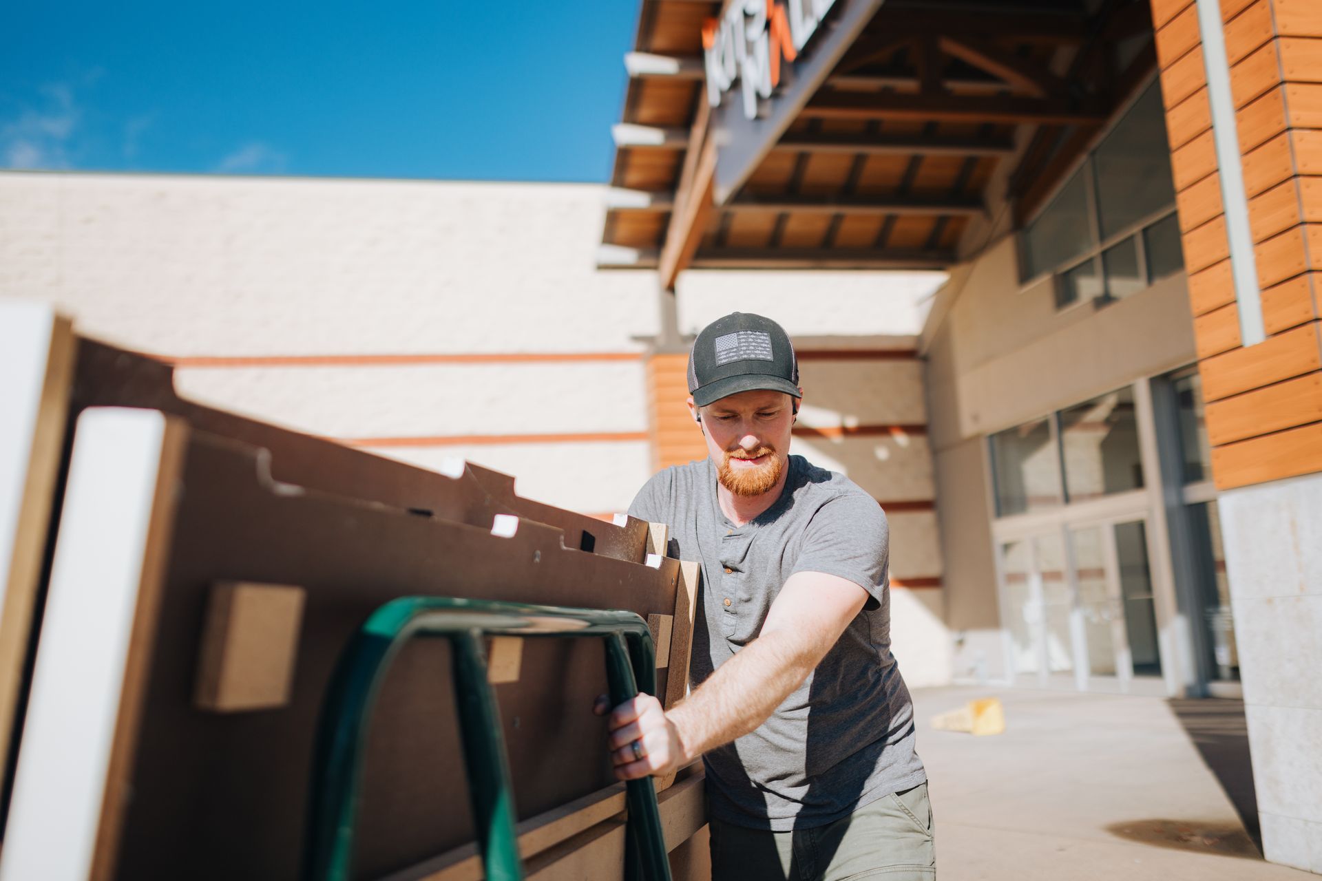 A man is pushing a cart full of boxes in front of a building.