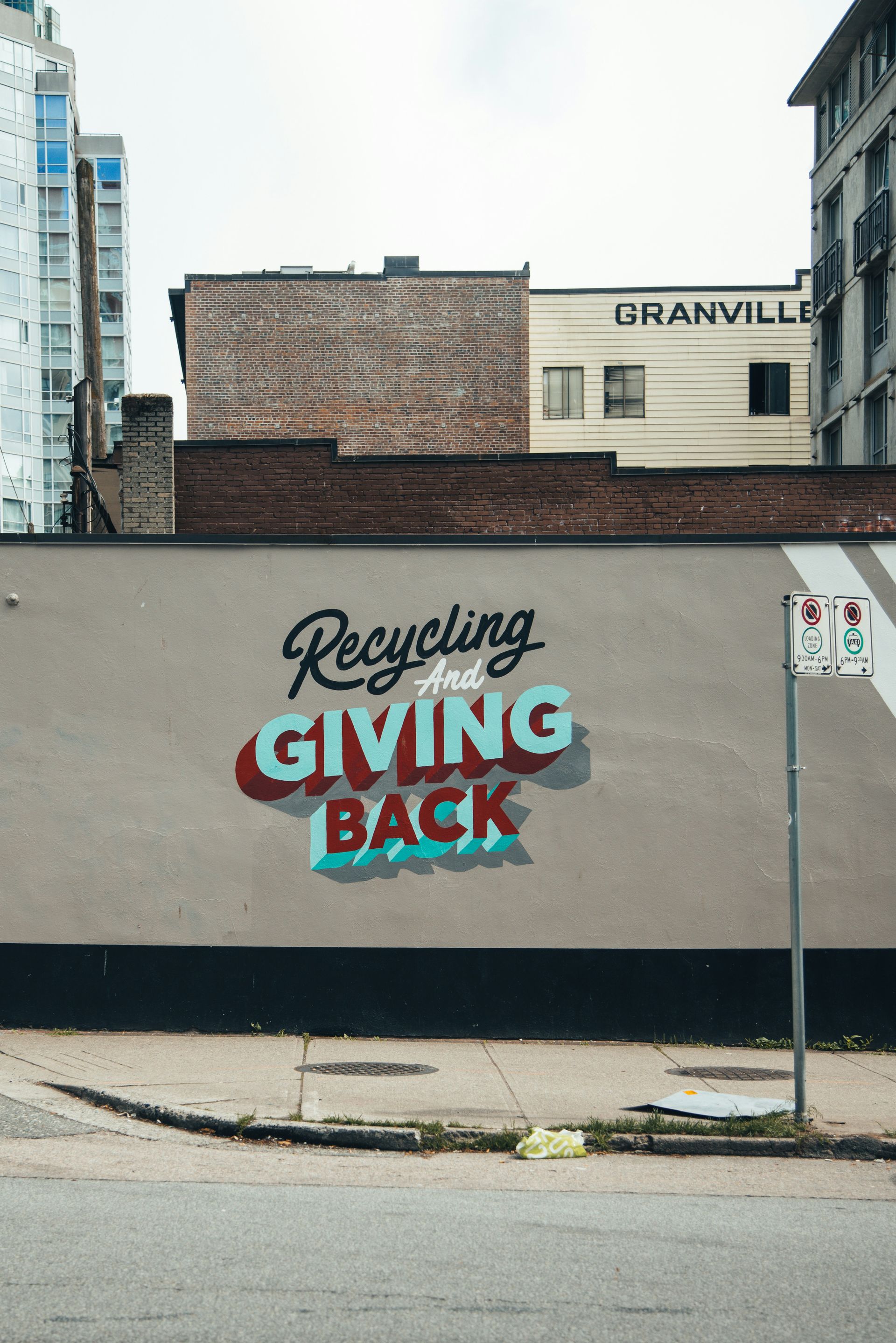 There is a mural on the side of a building that says `` recycling and giving back ''.