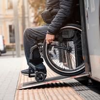 Person in wheelchair exiting a train using a ramp.