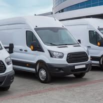 White delivery vans parked in a row in front of a building.
