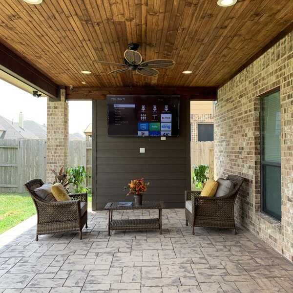 A patio with chairs and a television on the wall
