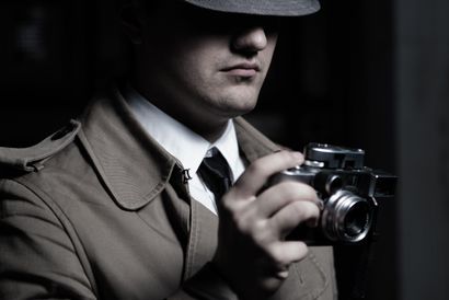 detective privato che scatta fotografie con un obiettivo potente