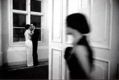 Donna che dietro la porta vede una coppia che si bacia