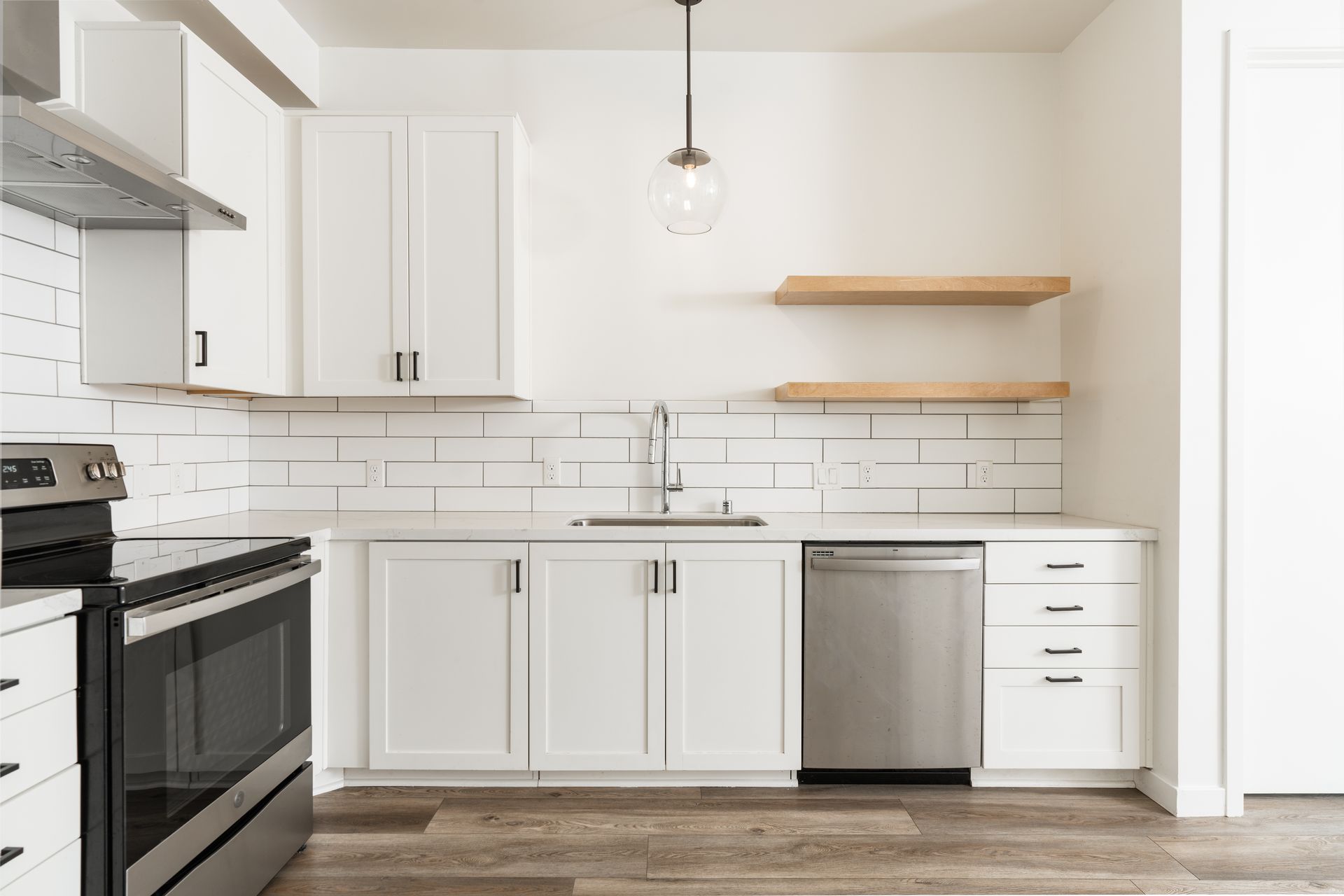 A kitchen with white cabinets , stainless steel appliances , a sink , and a stove.