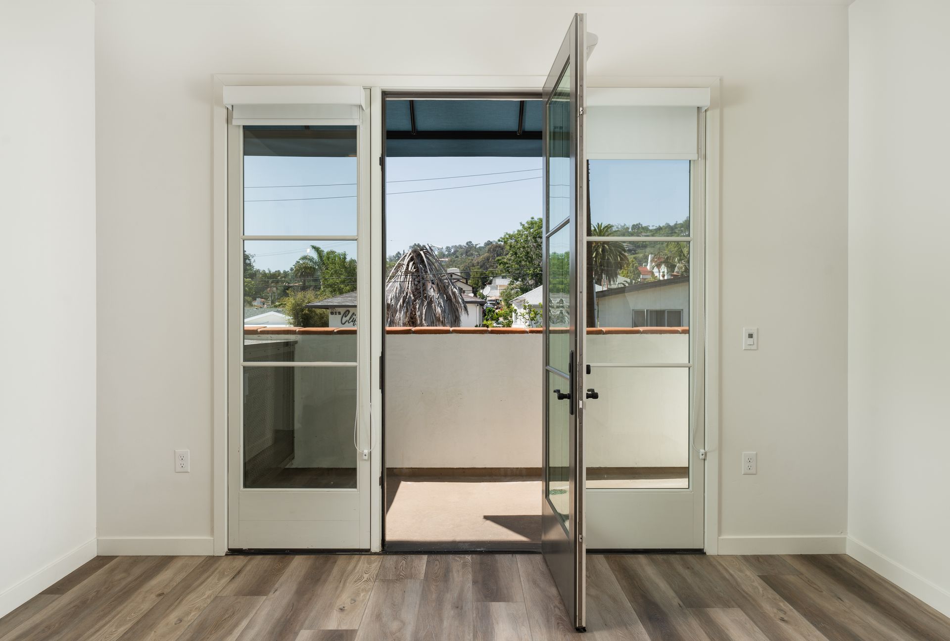 An empty room with a balcony and sliding glass doors leading to it.