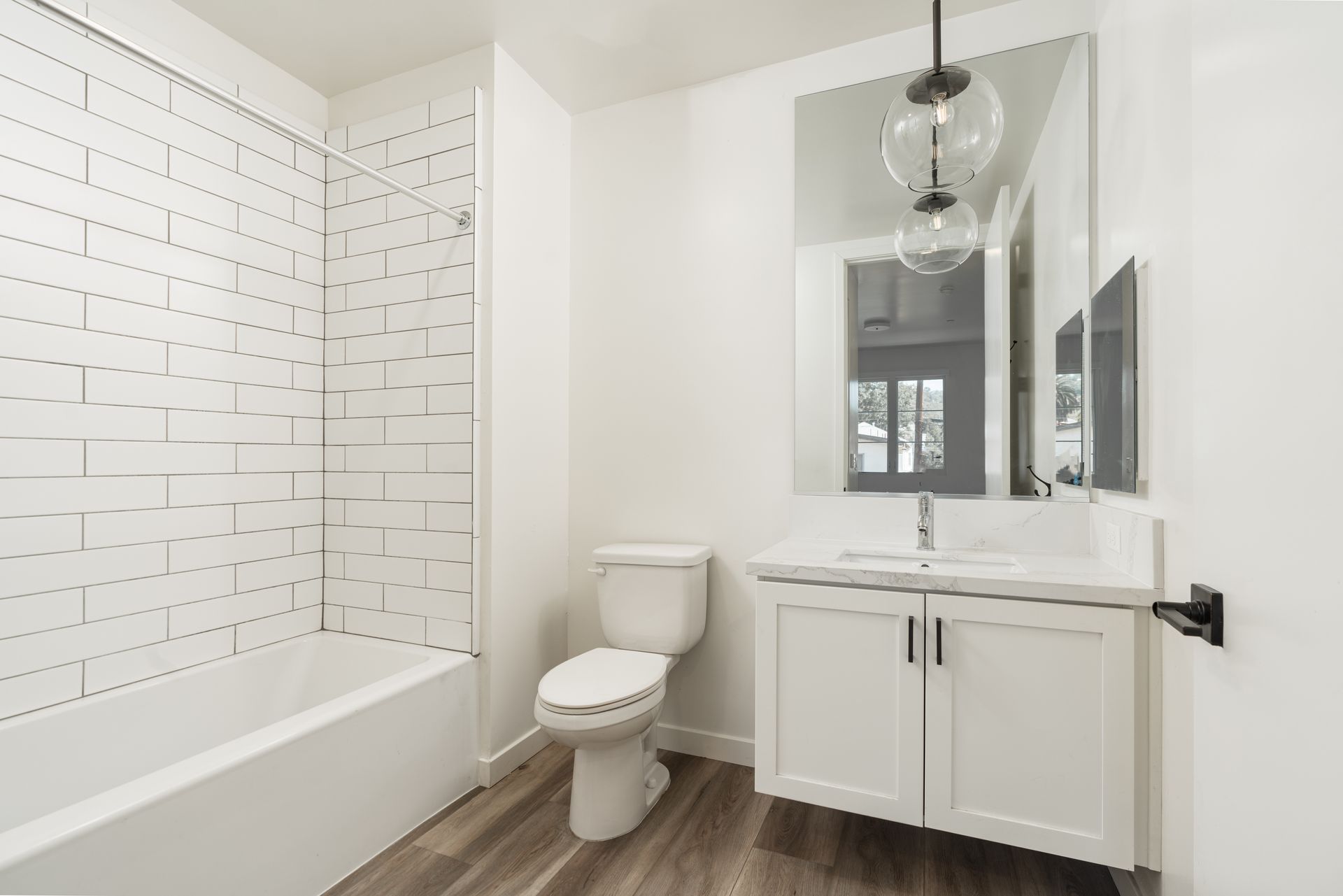 A bathroom with a toilet , sink , bathtub and mirror.