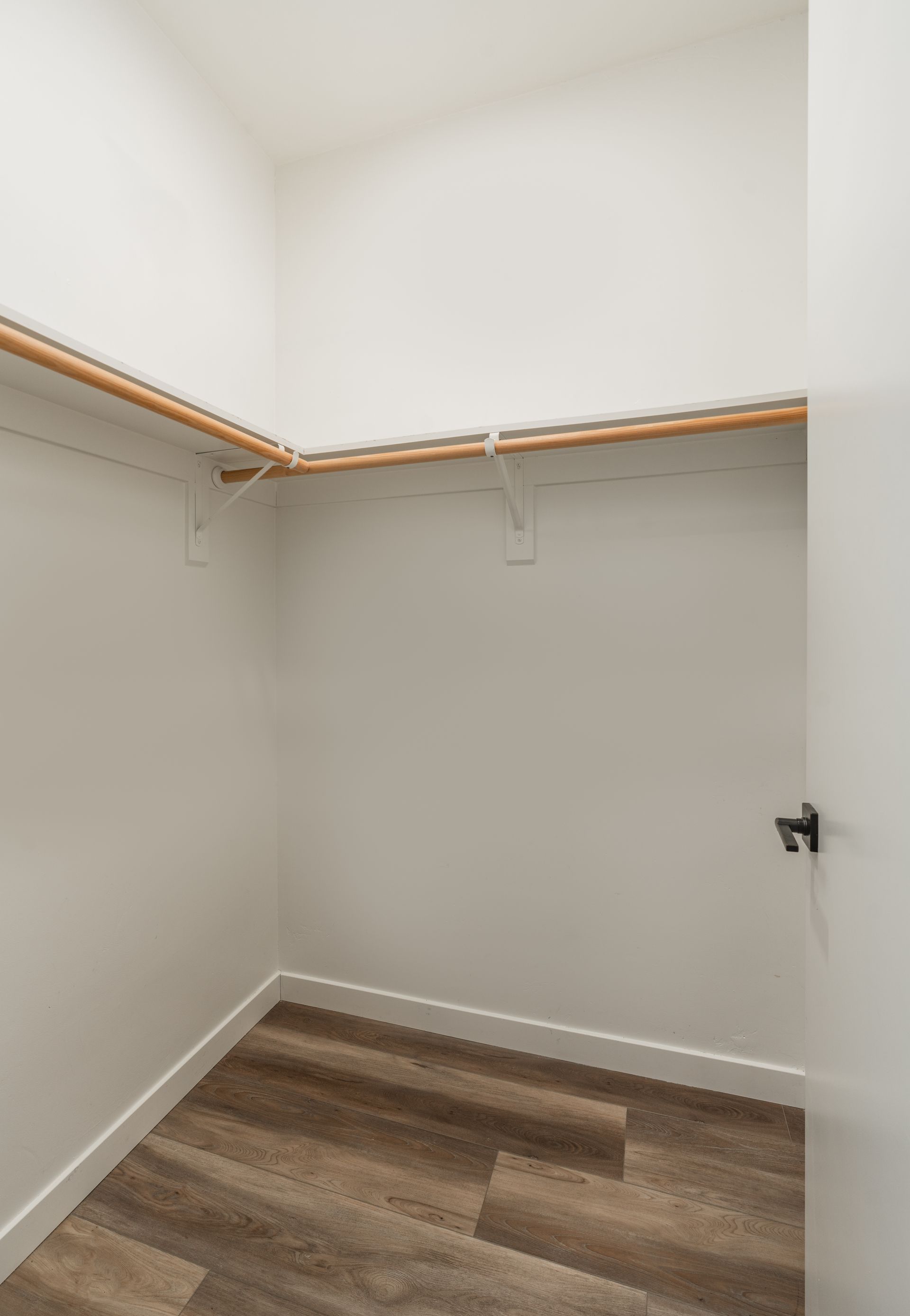 An empty walk in closet with wooden floors and shelves.