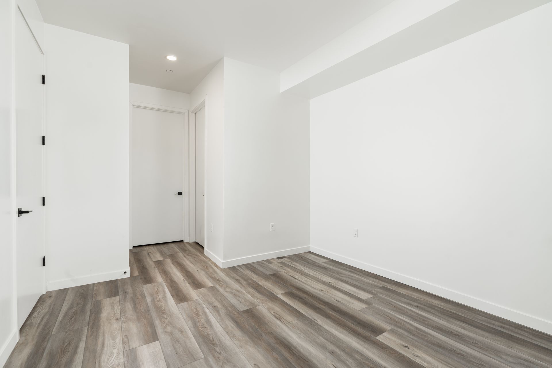 An empty room with hardwood floors and white walls.