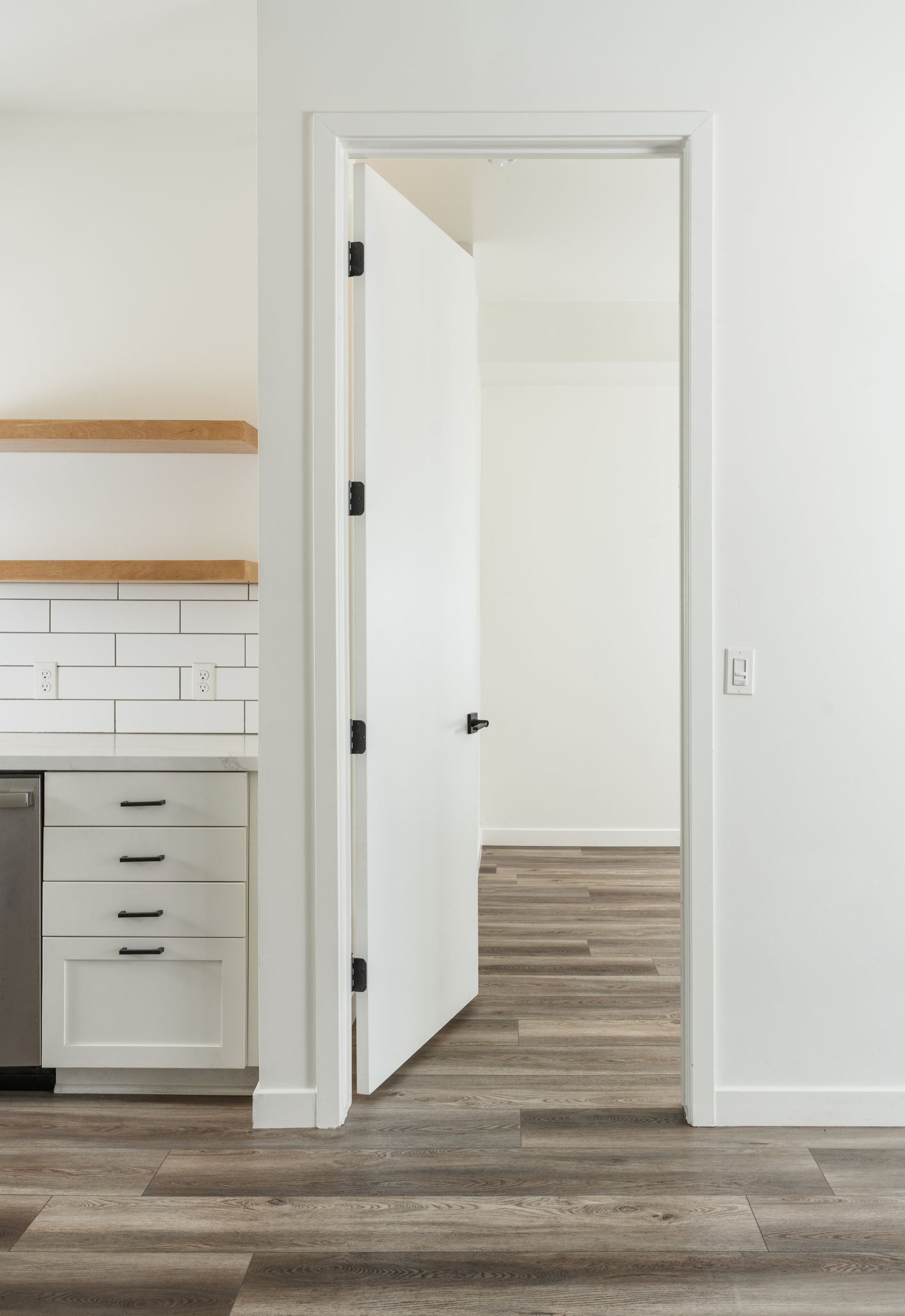 A kitchen with a door open leading to a hallway.