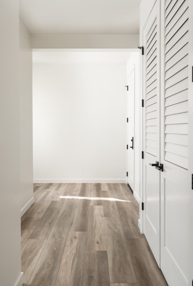 A hallway with a wooden floor and white doors