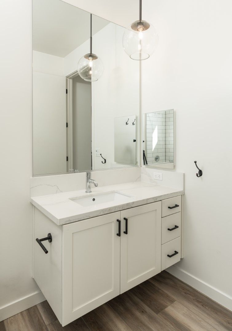 A bathroom with a sink , mirror and cabinets