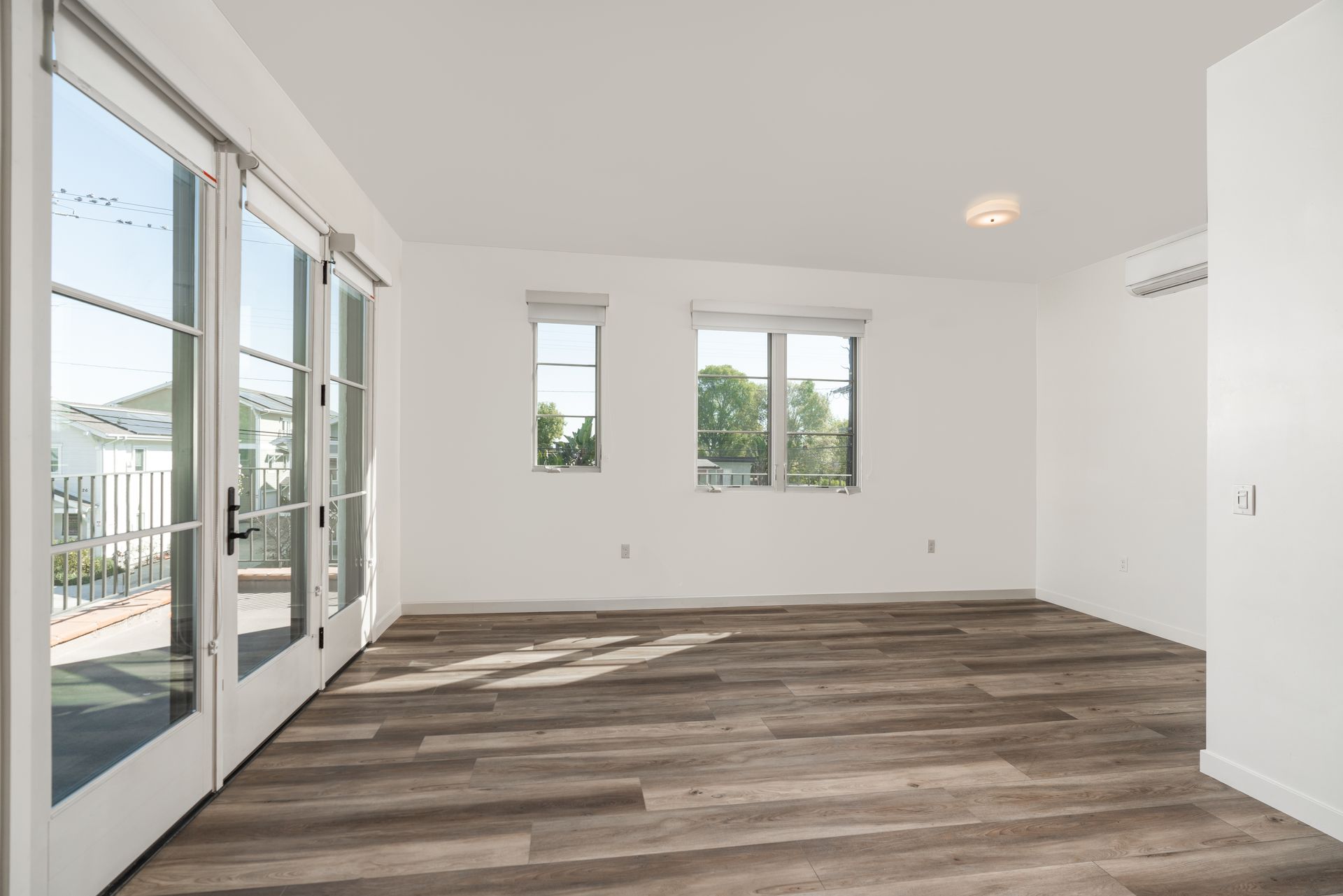 An empty living room with hardwood floors and white walls