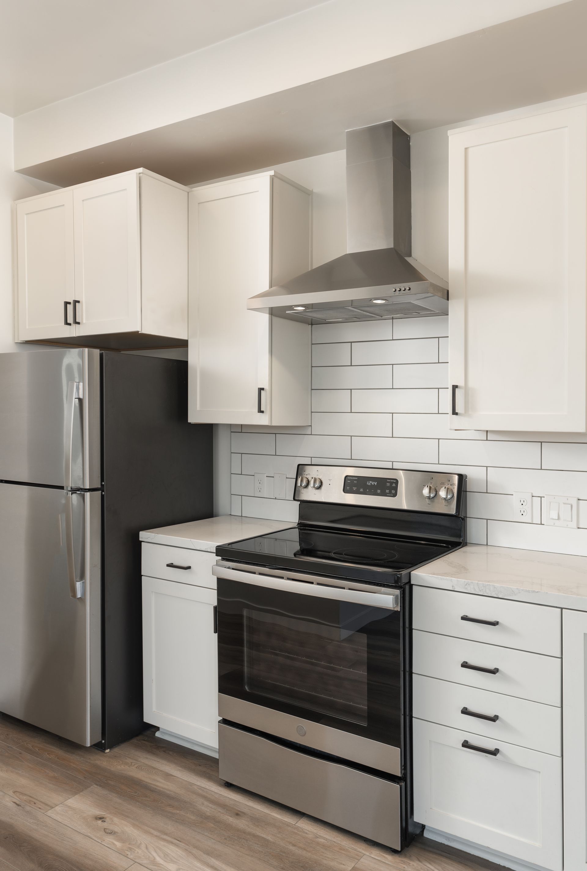 A kitchen with stainless steel appliances , white cabinets , a refrigerator and a stove.