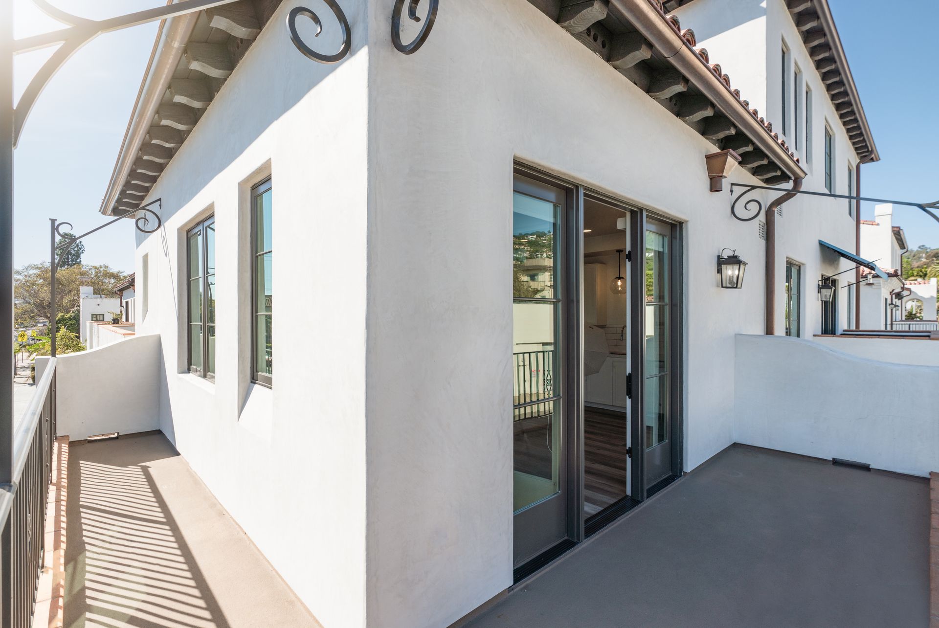 A white house with a balcony and sliding glass doors.