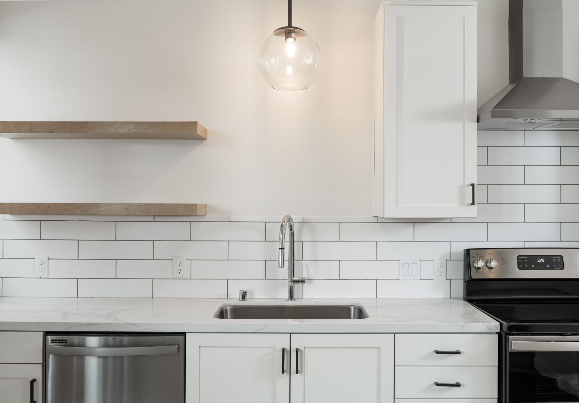 A kitchen with white cabinets , a sink , a stove , and a dishwasher.