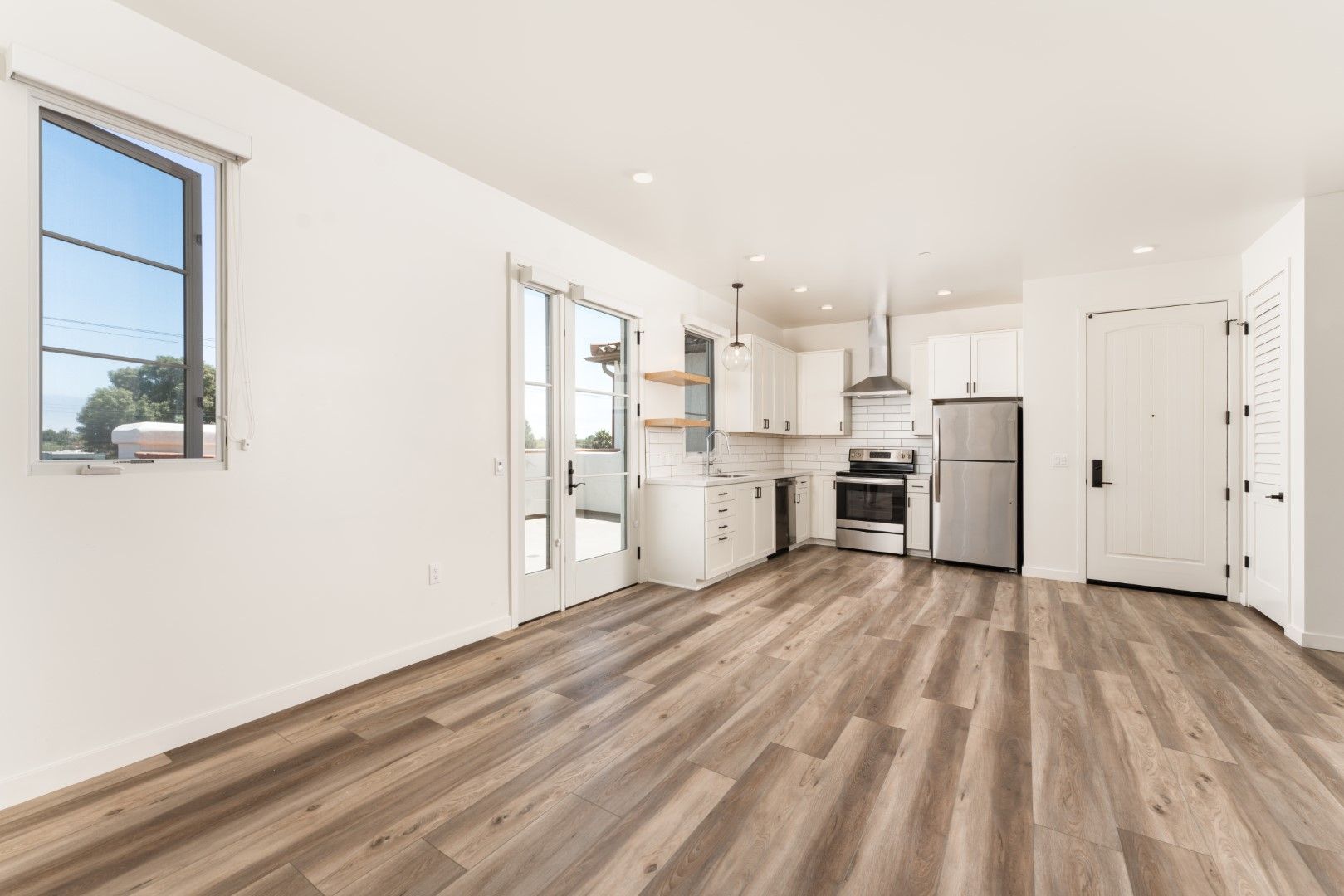 A living room with hardwood floors and a kitchen in the background.