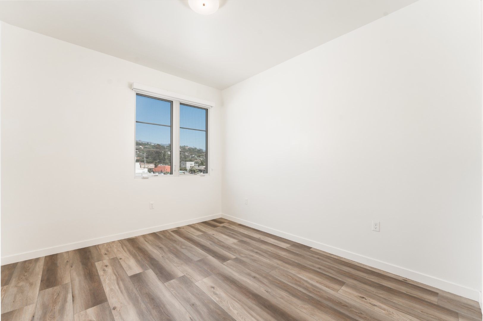 An empty bedroom with hardwood floors and two windows.